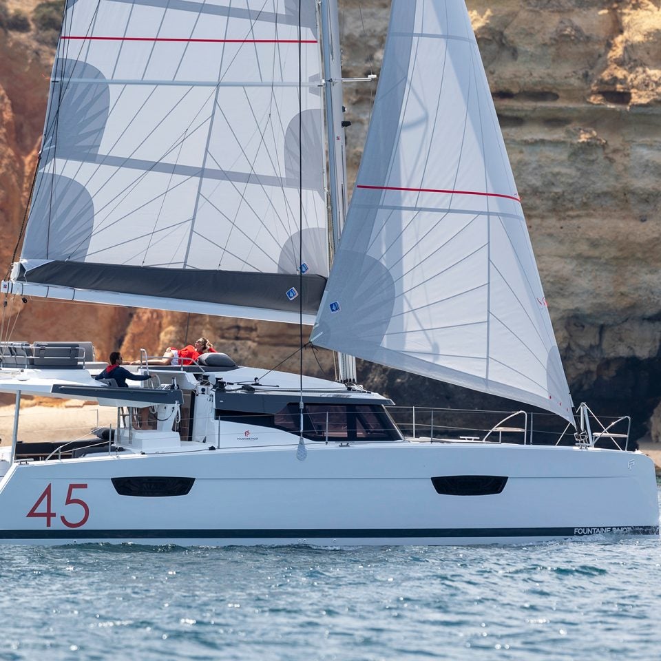Catamaran Fountaine Pajot Elba 45 naviguant près de la côte escarpée