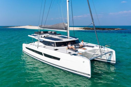Fountaine Pajot Aura 51 electric sailing catamaran at anchor near beach
