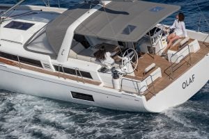 Vue du cockpit du voilier Oceanis Yacht 54 avec une femme à la barre