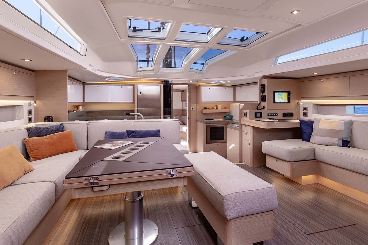 Espace de repas du salon intérieur du monocoque Dufour 61 avec de grands puits de lumière